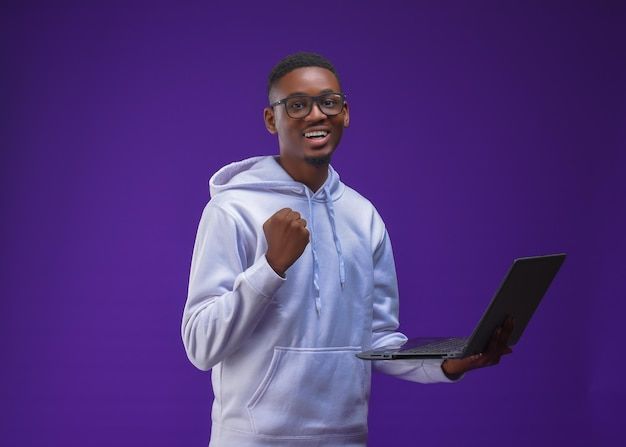 Premium Photo _ Handsome male in glasses smiling_ happy ecstatic African student holding laptop wearing a hoodie